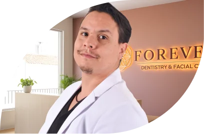 Smiling maxillofacial surgeon portrait with Forever Dentistry clinic branding overlay